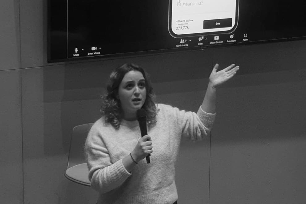 Manon, micro à la main, présente un projet devant un écran qui affiche une maquette d'application mobile